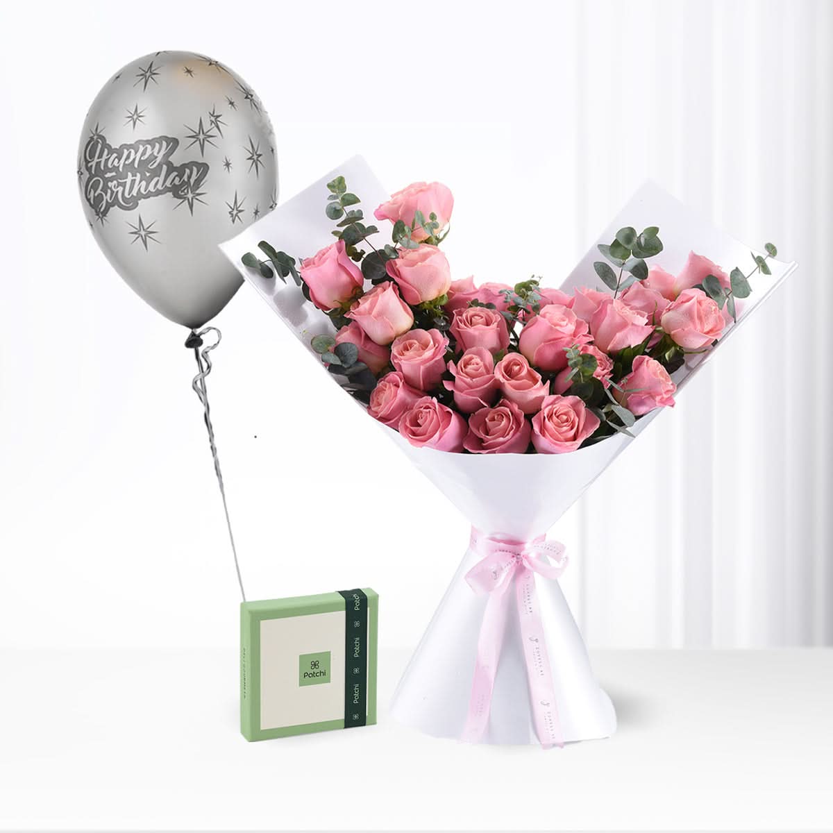 Pink roses bouquet with silver "Happy Birthday" balloon and green gift box.