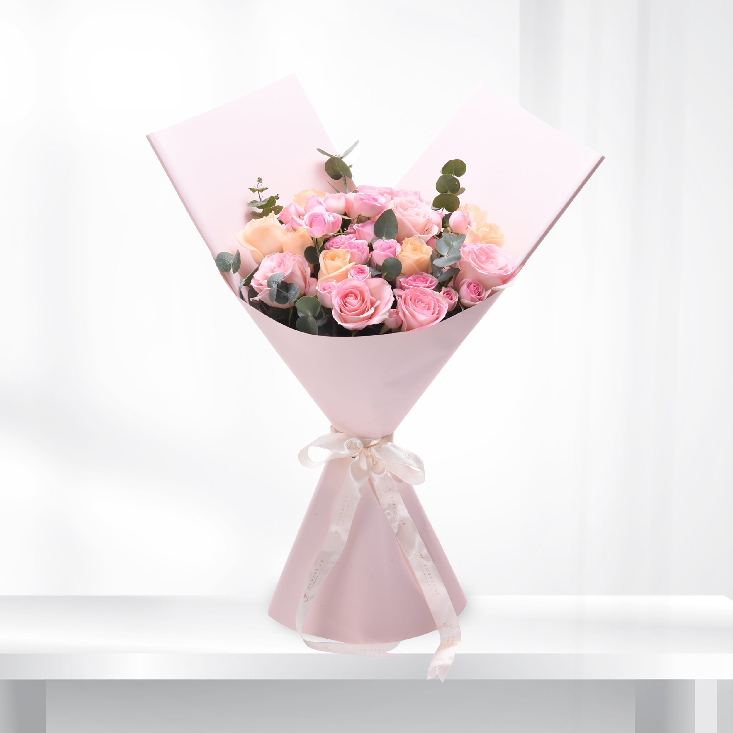 Soft pink roses and eucalyptus wrapped in pastel paper with elegant ribbon.