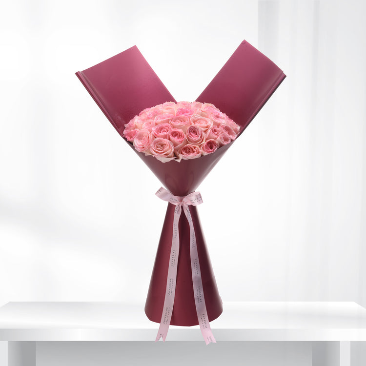 Soft pink roses elegantly wrapped in burgundy paper with branded ribbon.