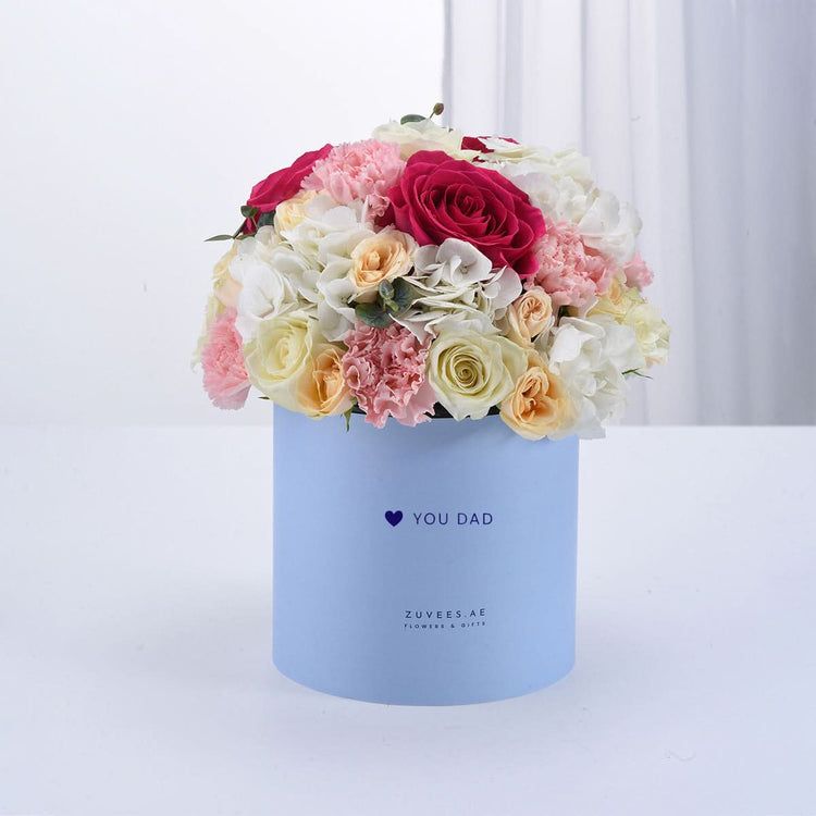 Pastel blue box holds vibrant pink, white, and peach roses and carnations.