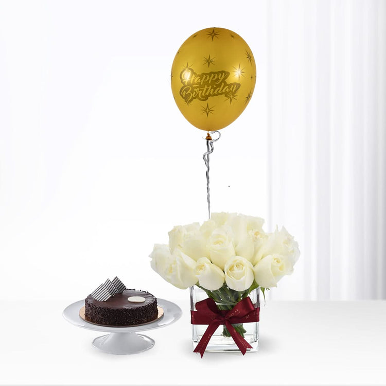 Golden "Happy Birthday" balloon floats above white roses and chocolate cake.