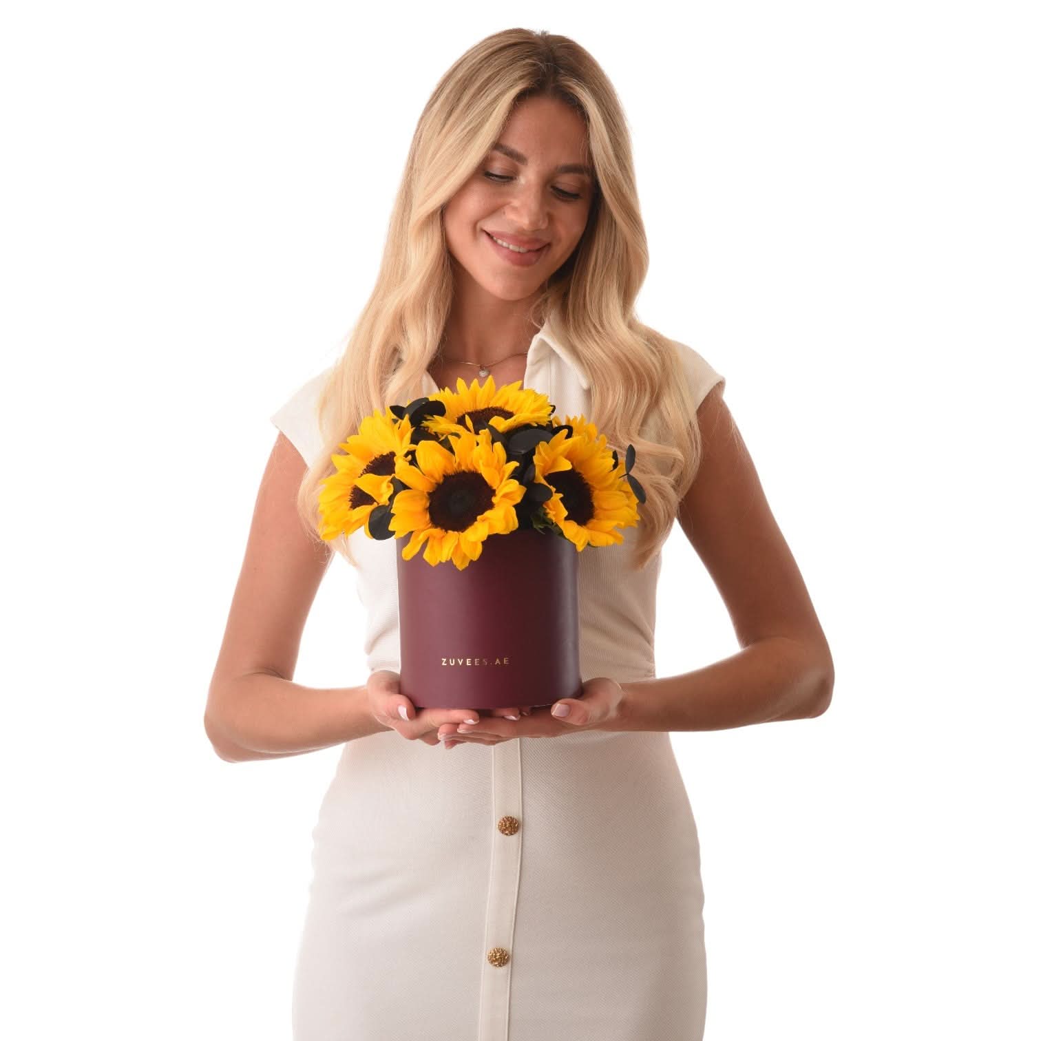 Woman holds burgundy box of vibrant yellow sunflowers with dark centers.