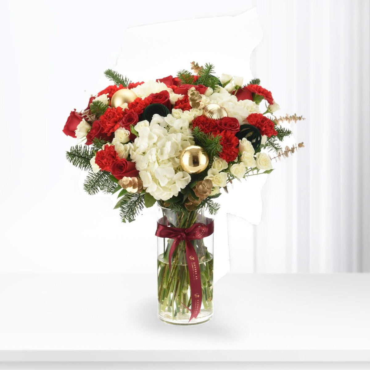 Vibrant red and white floral arrangement with gold ornaments in clear vase.