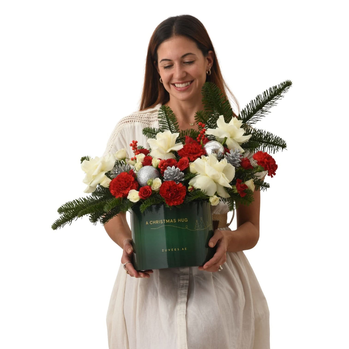 Woman holds festive green bucket with red/white blooms and pine, labeled "A CHRISTMAS HUG".