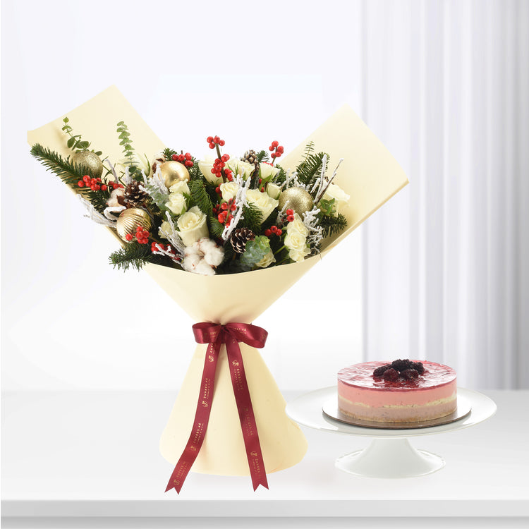Elegant cream-wrapped floral bouquet with gold ornaments, red berries, and pine, beside a layered berry cake.