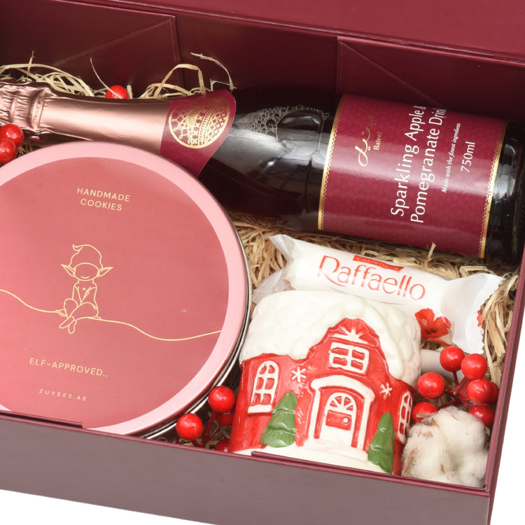 Luxury holiday gift box with festive treats, sparkling drink, and red berry accents.