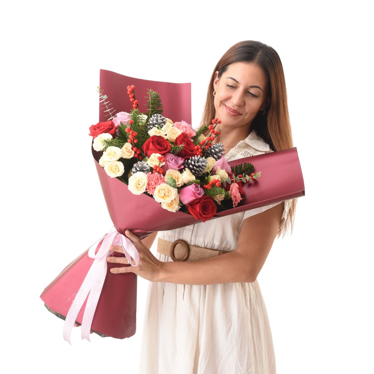 Woman smiles holding vibrant red, pink, and cream rose bouquet wrapped in burgundy paper.