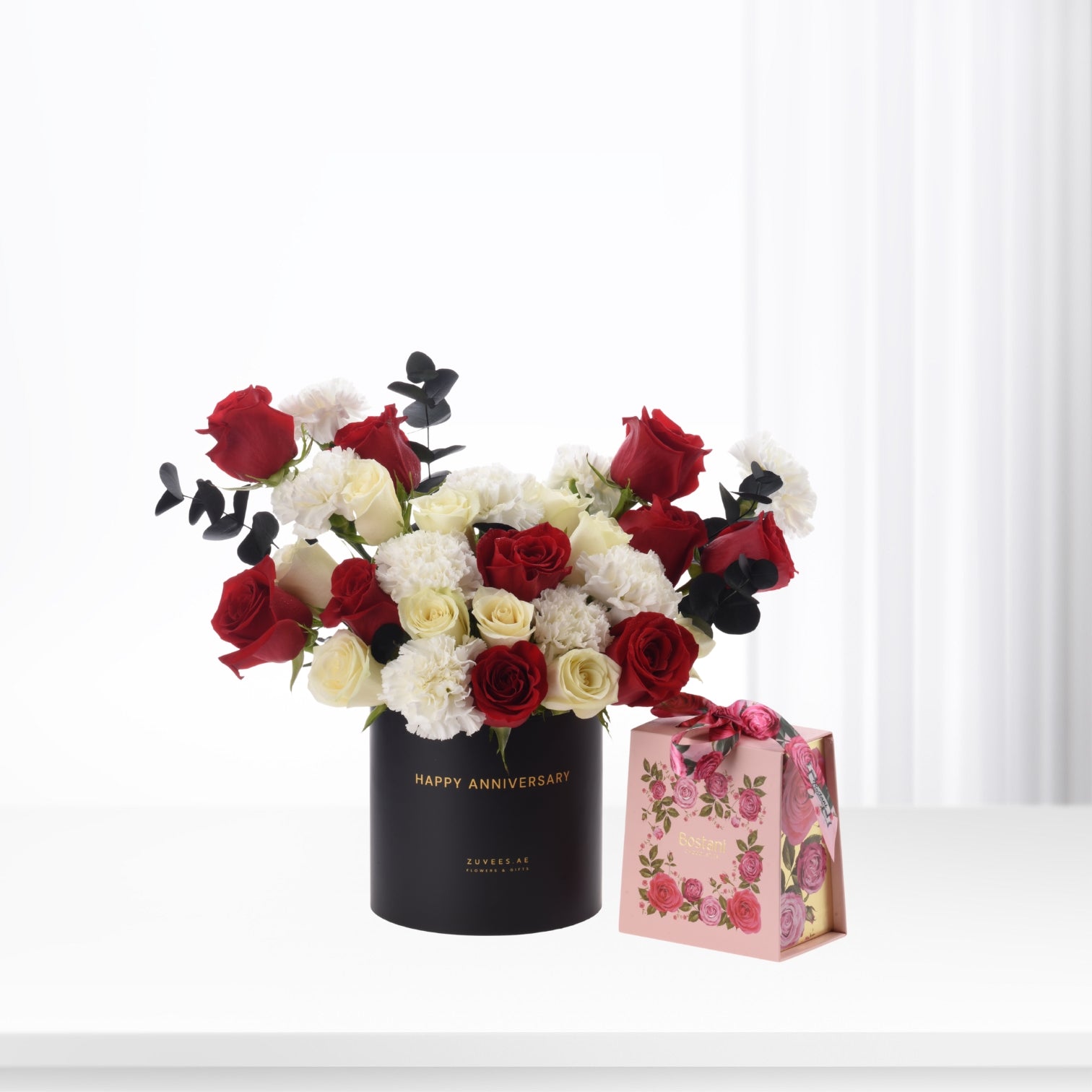 Elegant red, white roses and carnations in black "Happy Anniversary" vase with pink floral gift box.