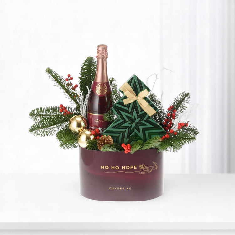 Elegant holiday gift basket with champagne, green star box, pine, berries, and gold ornaments.
