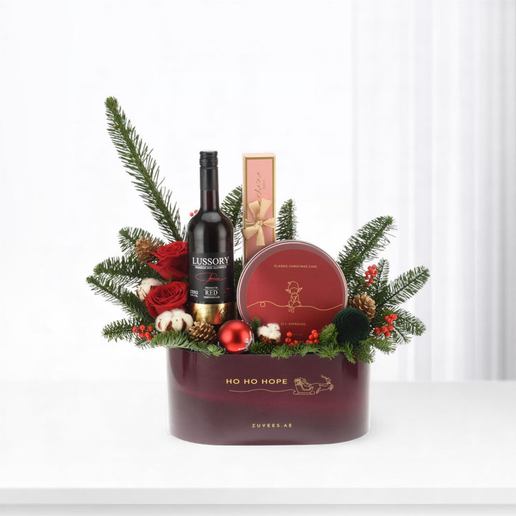 Elegant burgundy holiday gift basket with festive greenery, red roses, and branded treats.