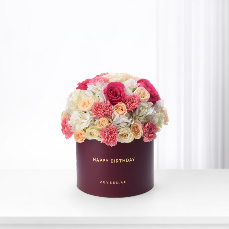 Vibrant pink, peach, and white roses and carnations in burgundy box reading "Happy Birthday".