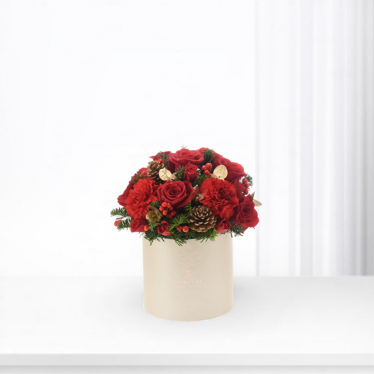 Vibrant red roses and carnations in beige box with pinecones and berries.