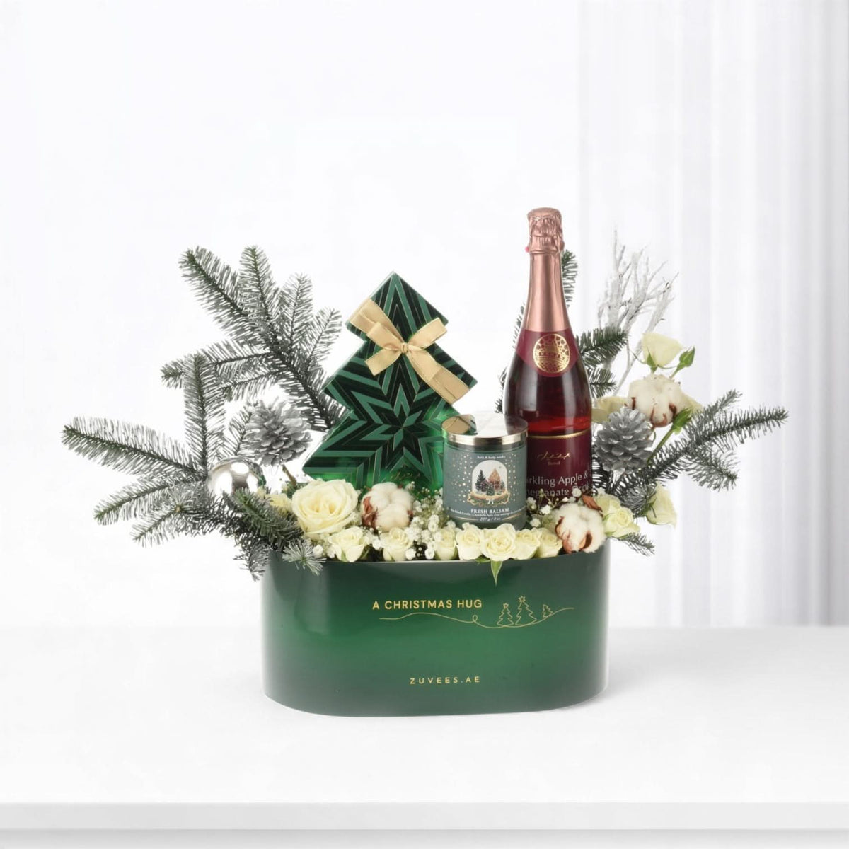 Elegant green Christmas gift basket with champagne, candle, and festive florals.