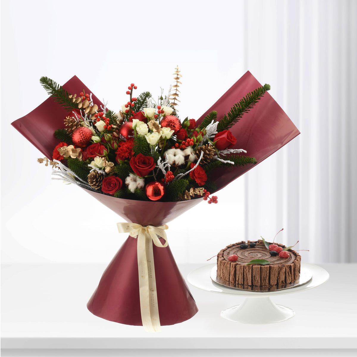 Vibrant red and white floral bouquet with festive ornaments, paired with chocolate cake.