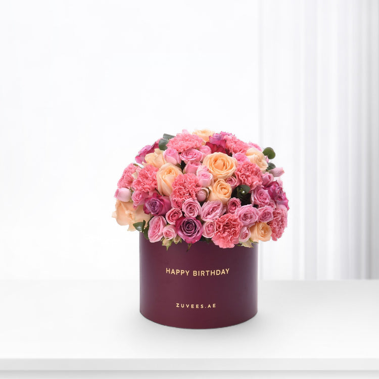 Vibrant pink and peach roses & carnations in burgundy box with "Happy Birthday" gold text.