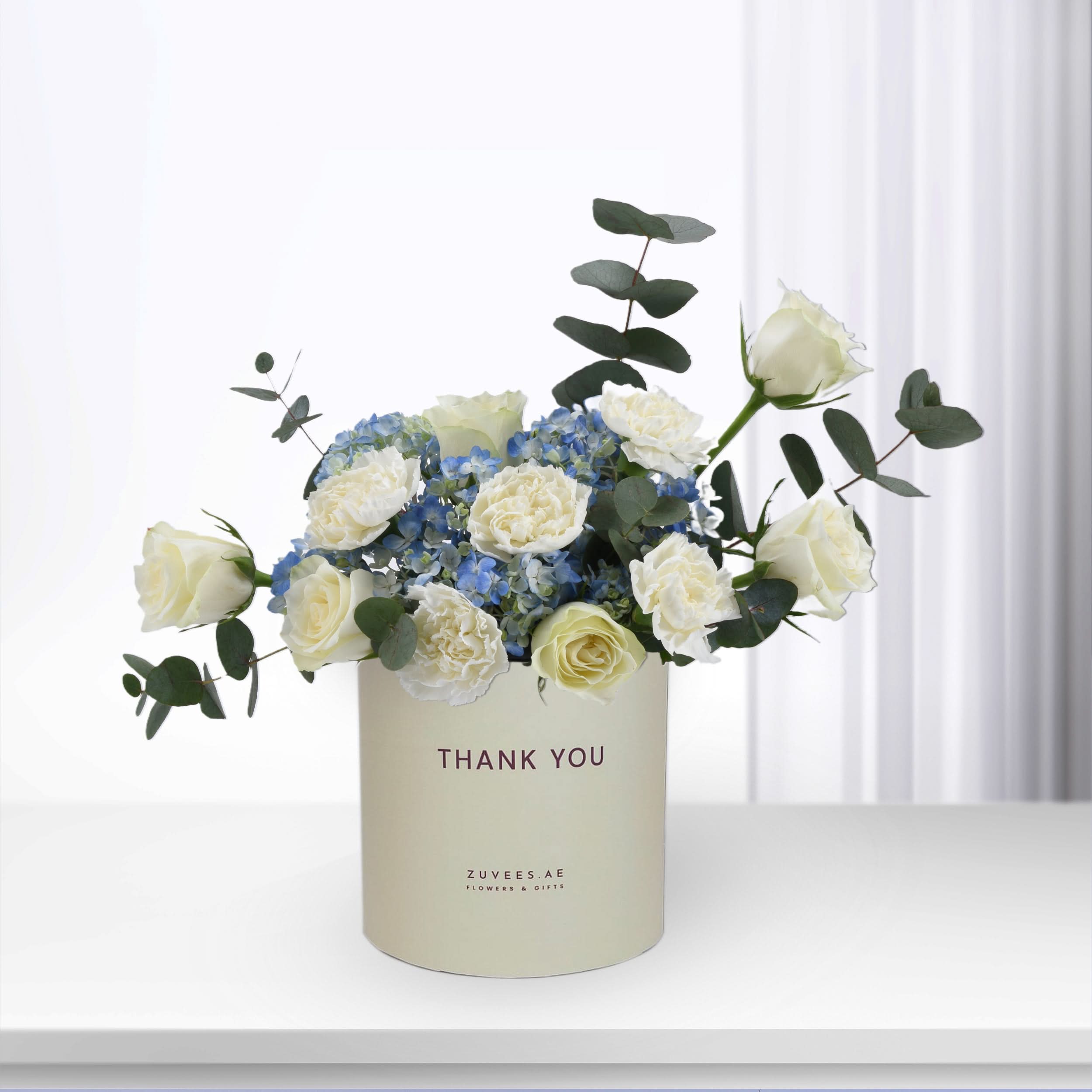 Elegant white roses and blue hydrangeas in minimalist cream "Thank You" gift box.