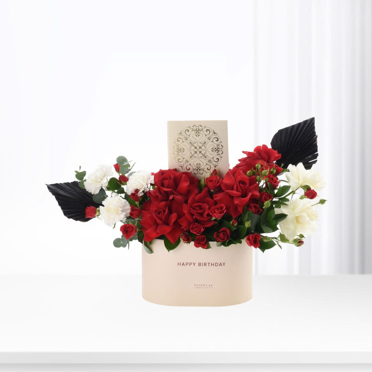 Elegant red and white floral arrangement in beige box with "Happy Birthday" text.