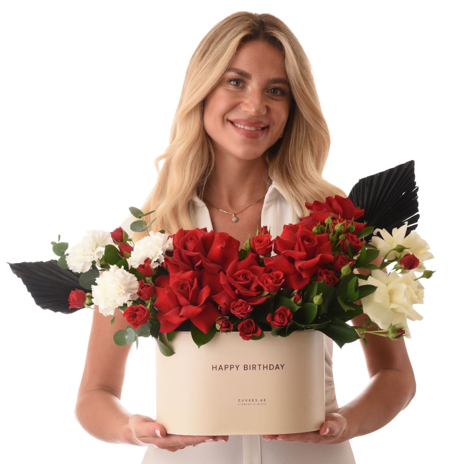Woman holds elegant birthday flower box with red roses and white blooms.
