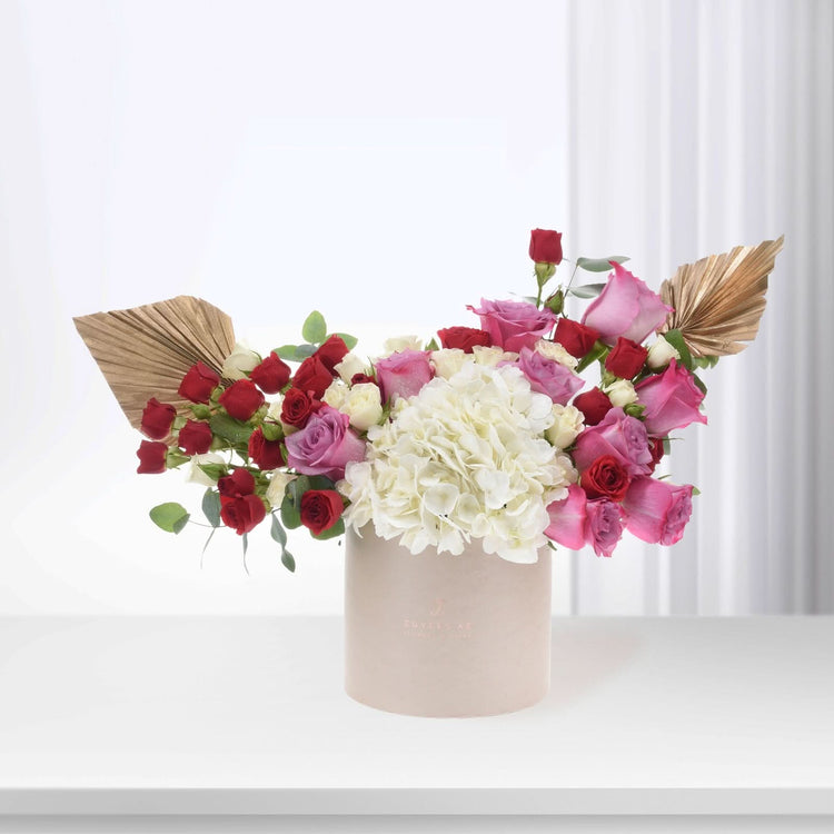 Elegant floral arrangement in blush box, featuring red, pink roses and white hydrangeas with gold accents.