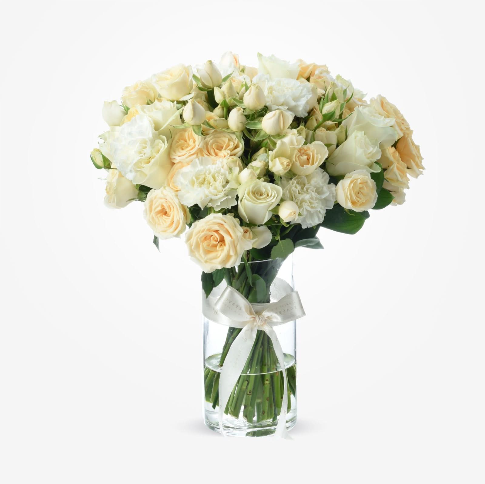 Elegant cream roses and carnations in clear vase with satin bow.
