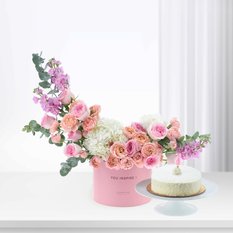 Pink floral arrangement with cake in minimalist white setting.