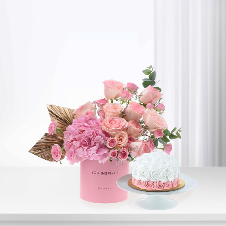 Pink roses and hydrangeas in branded box beside white rose cake.
