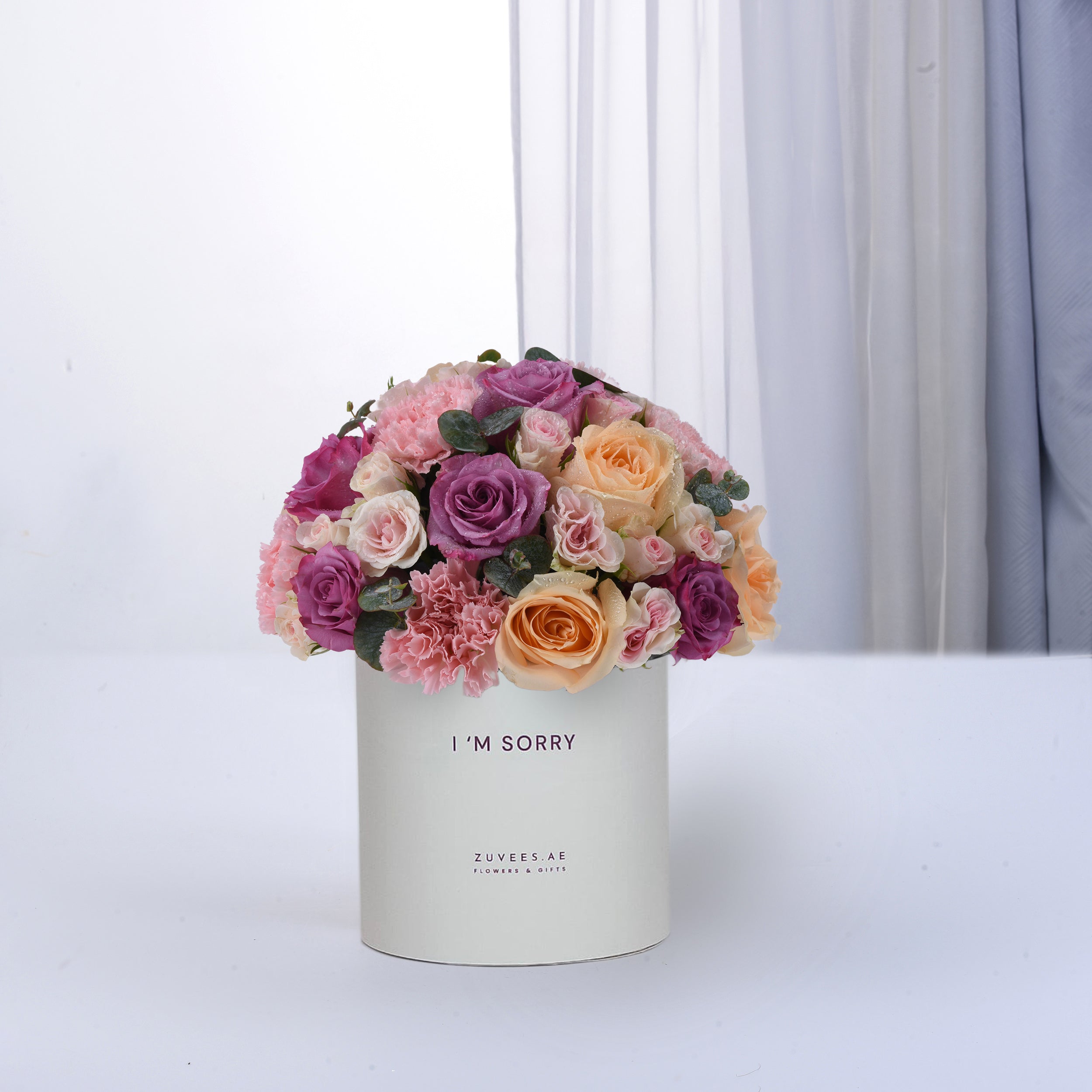Pastel pink, purple, and peach roses in white box reading "I&