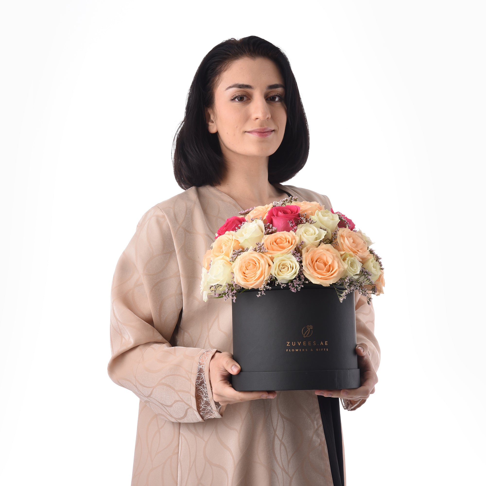 Elegant woman holds black box of vibrant multi-colored roses.