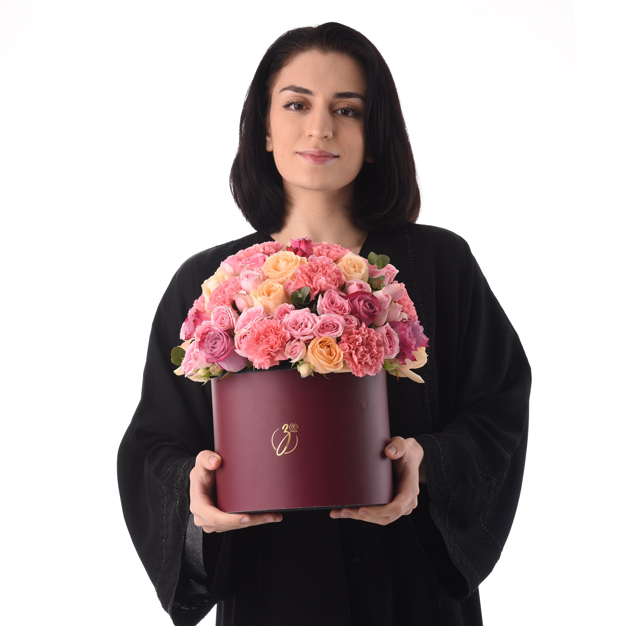 Woman holds burgundy hat box filled with pink and peach roses.
