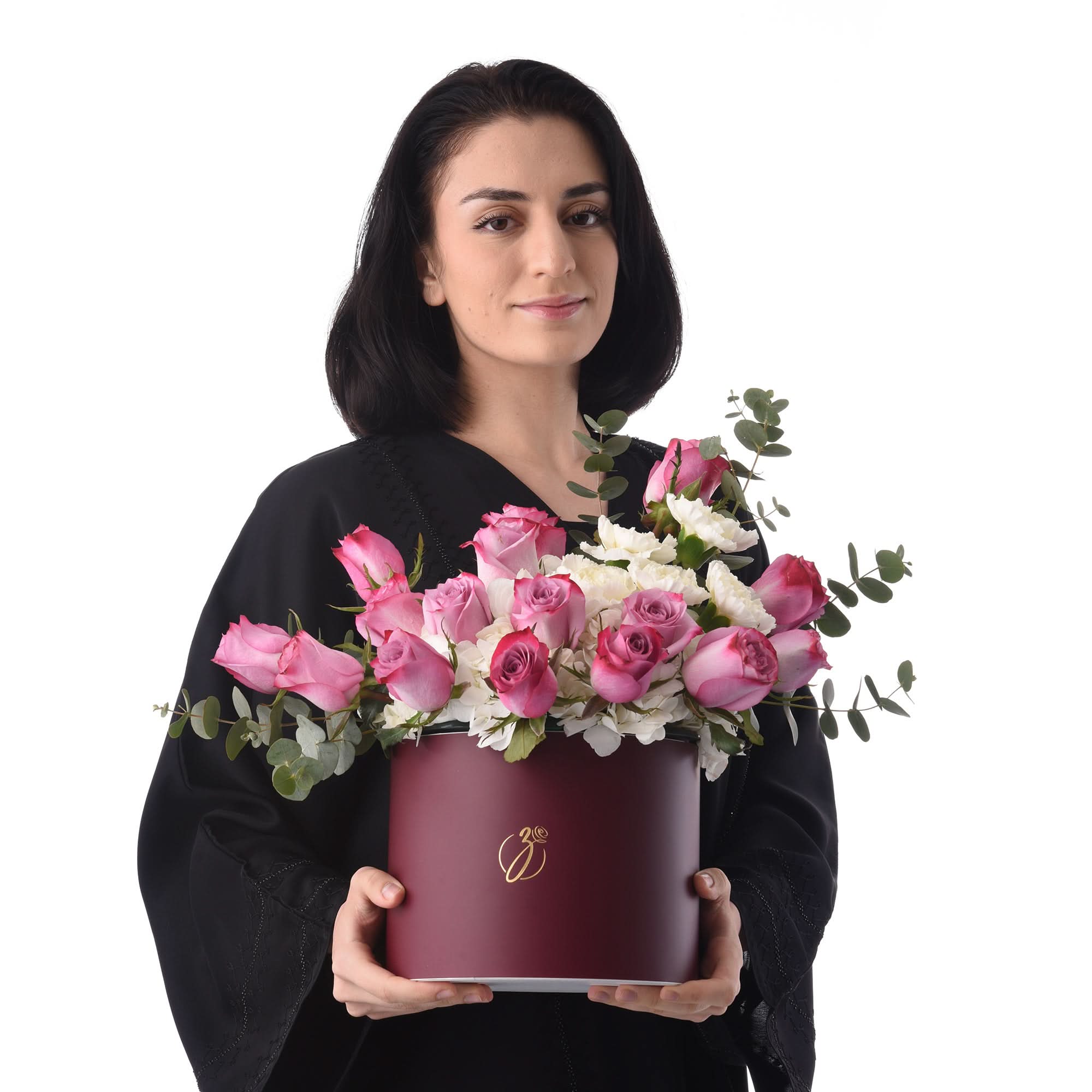 Woman holds burgundy hat box filled with pink roses and white blooms.