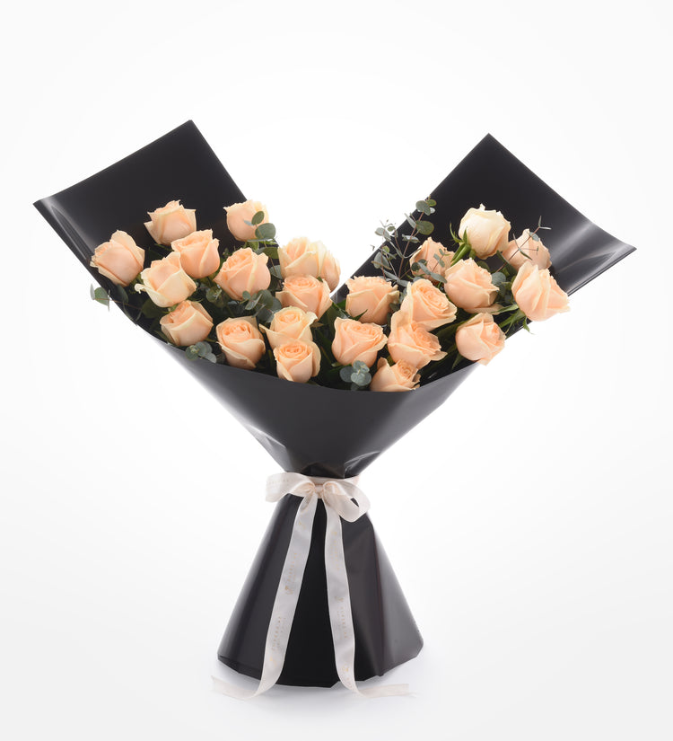 Soft peach roses elegantly wrapped in glossy black paper with cream ribbon.