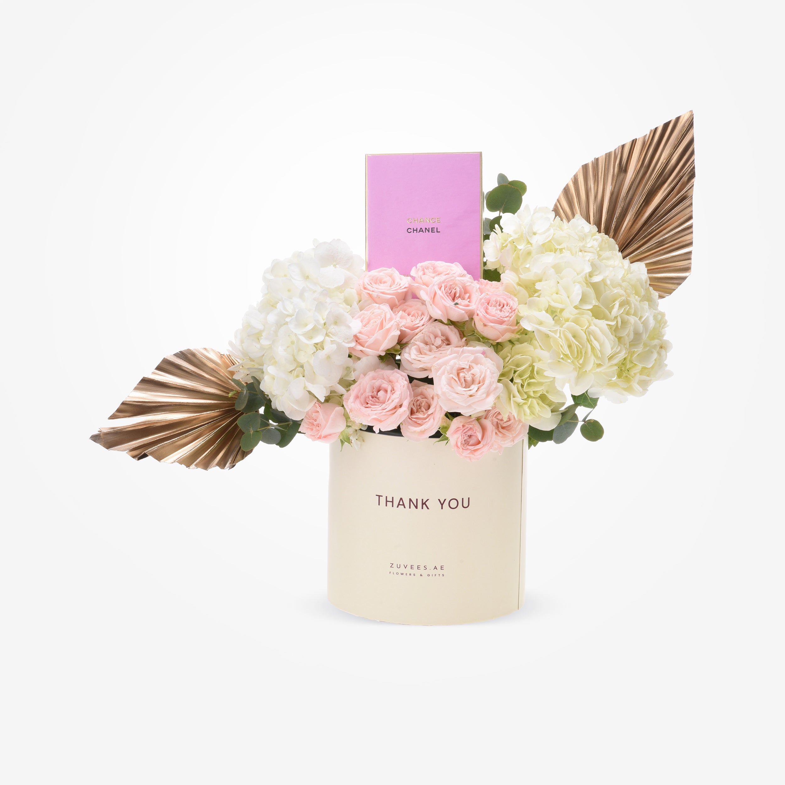 Elegant pink roses and hydrangeas in cream cylinder with gold accents and Chanel perfume.