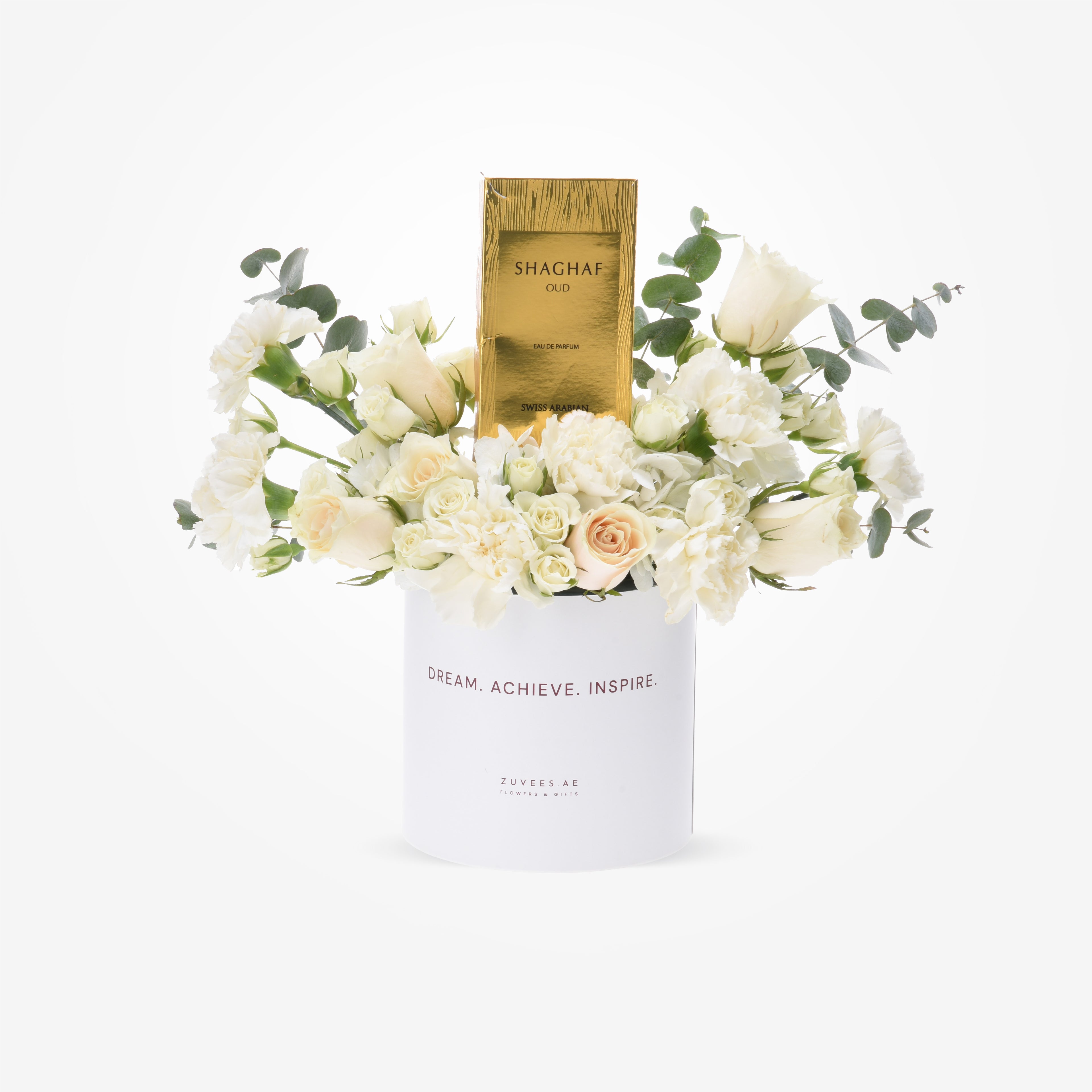 White floral arrangement with gold perfume box in branded white cylinder.