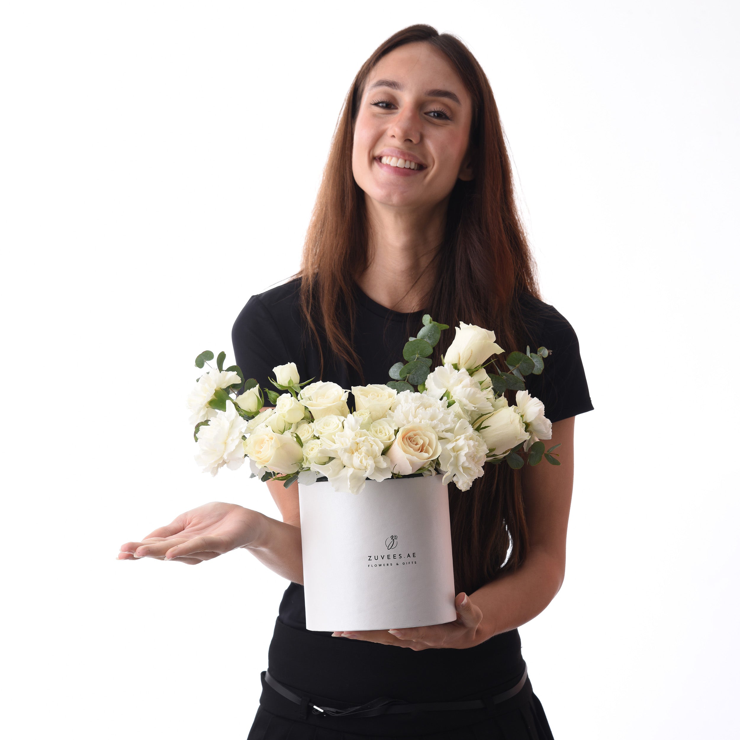 White rose bouquet in branded box, held by smiling woman against clean background.