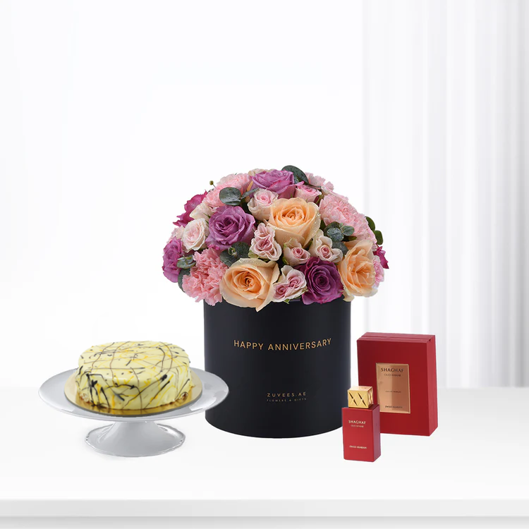 Luxurious anniversary gift set: roses, cake, perfume in elegant black and red packaging.