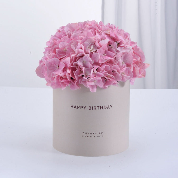 Soft pink hydrangeas in minimalist beige box, "Happy Birthday" printed.