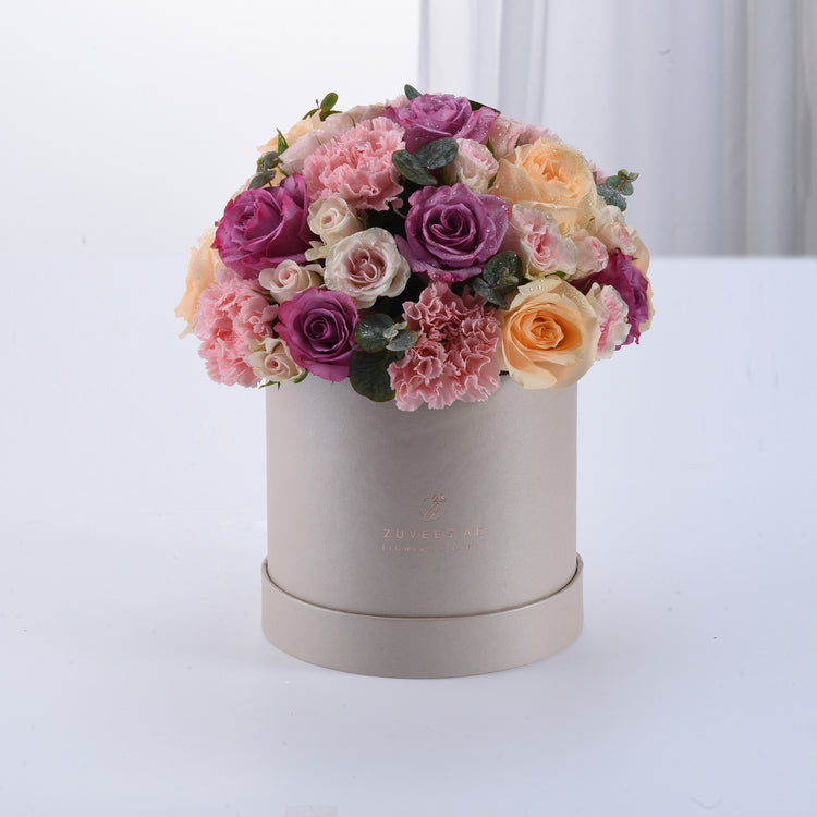Elegant pastel roses and carnations in matte silver hat box.