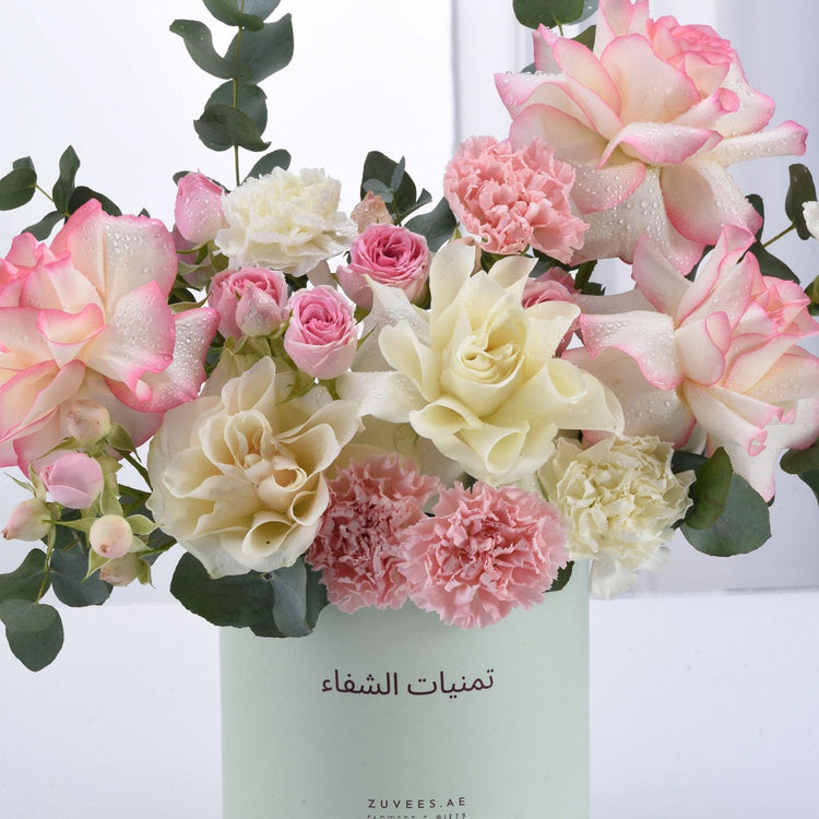 Pastel pink and cream roses with carnations, dew drops, and eucalyptus in mint vase.