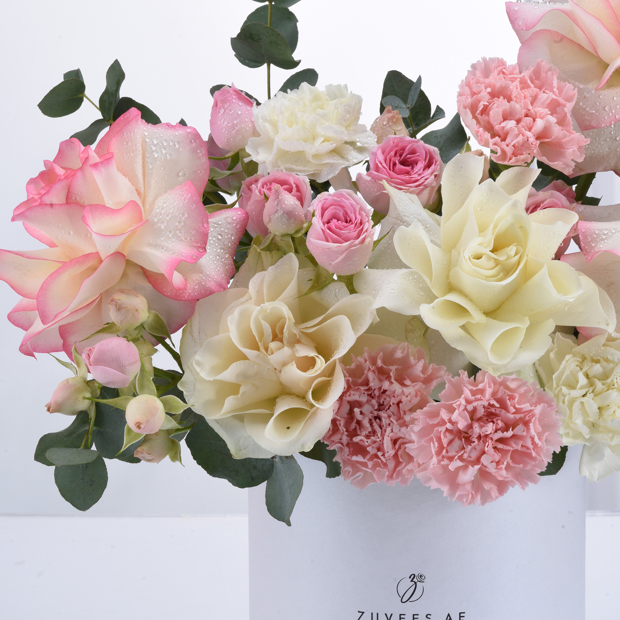 Soft pink and cream roses, carnations, and eucalyptus with dewdrops.