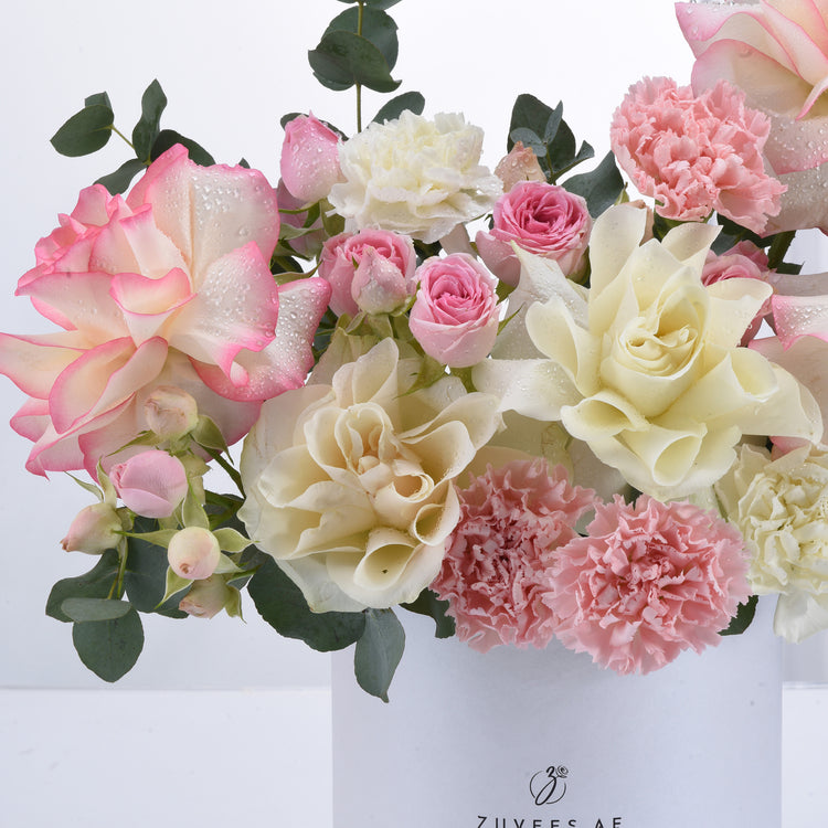 Soft pink and cream roses, carnations, and eucalyptus with dewdrops.
