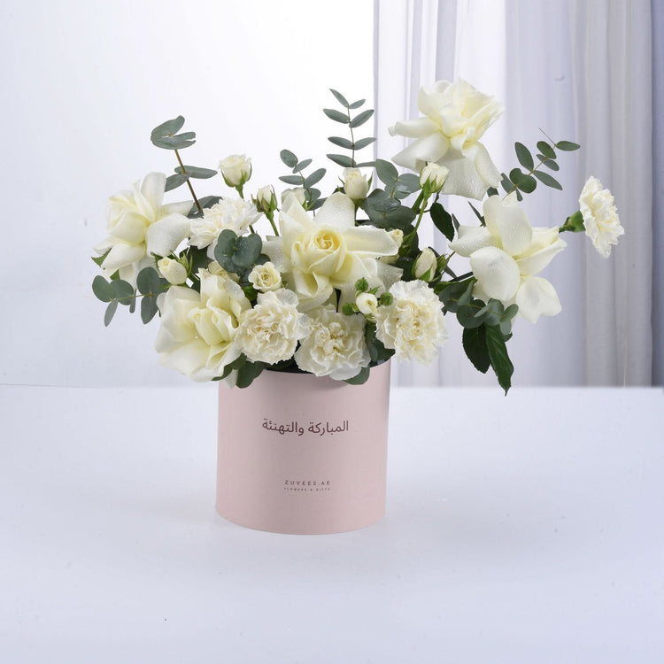 Soft white roses and carnations in pink box with Arabic greeting.