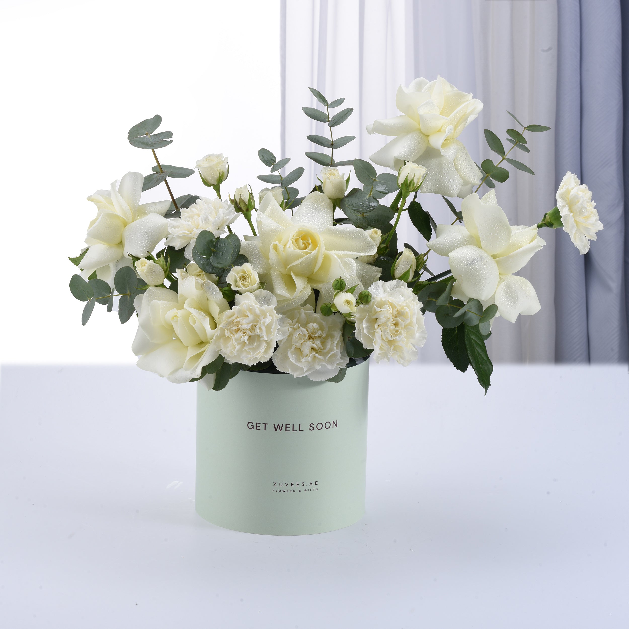 White roses and carnations in mint-green "Get Well Soon" box.