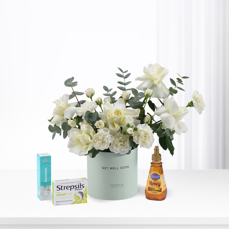 White roses and eucalyptus in mint vase with honey, throat lozenges, and electrolyte for recovery.
