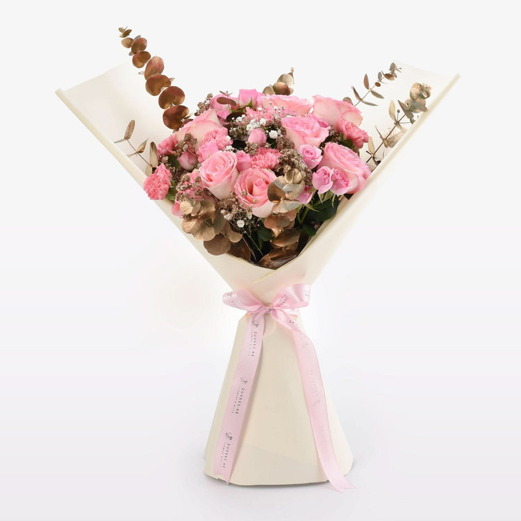 Soft pink roses, eucalyptus, and baby’s breath in cream wrap with pink ribbon.