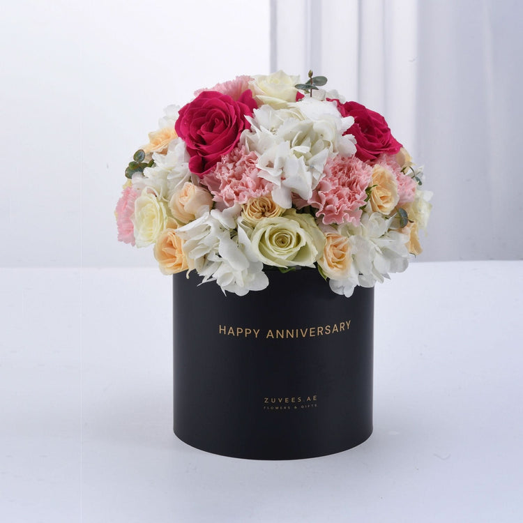 Elegant black box filled with vibrant pink, white, and cream roses and hydrangeas, celebrating anniversary.