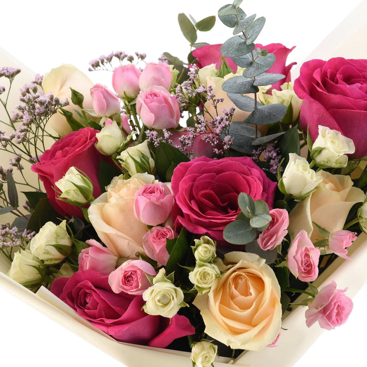 Vibrant pink, peach, white roses with eucalyptus, lavender filler in elegant cream wrap.