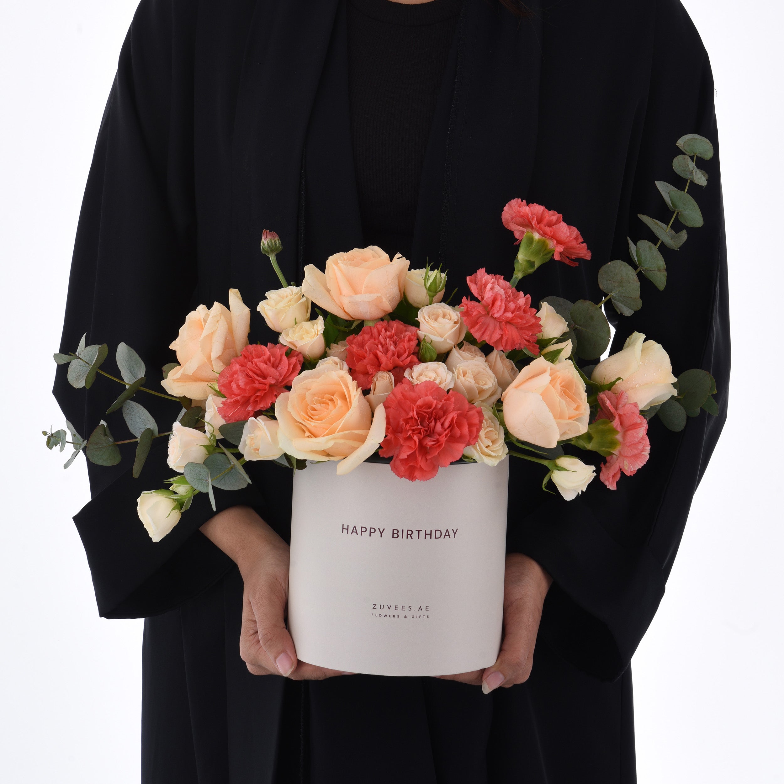 Elegant peach roses, coral carnations, and eucalyptus in a "Happy Birthday" gift box.