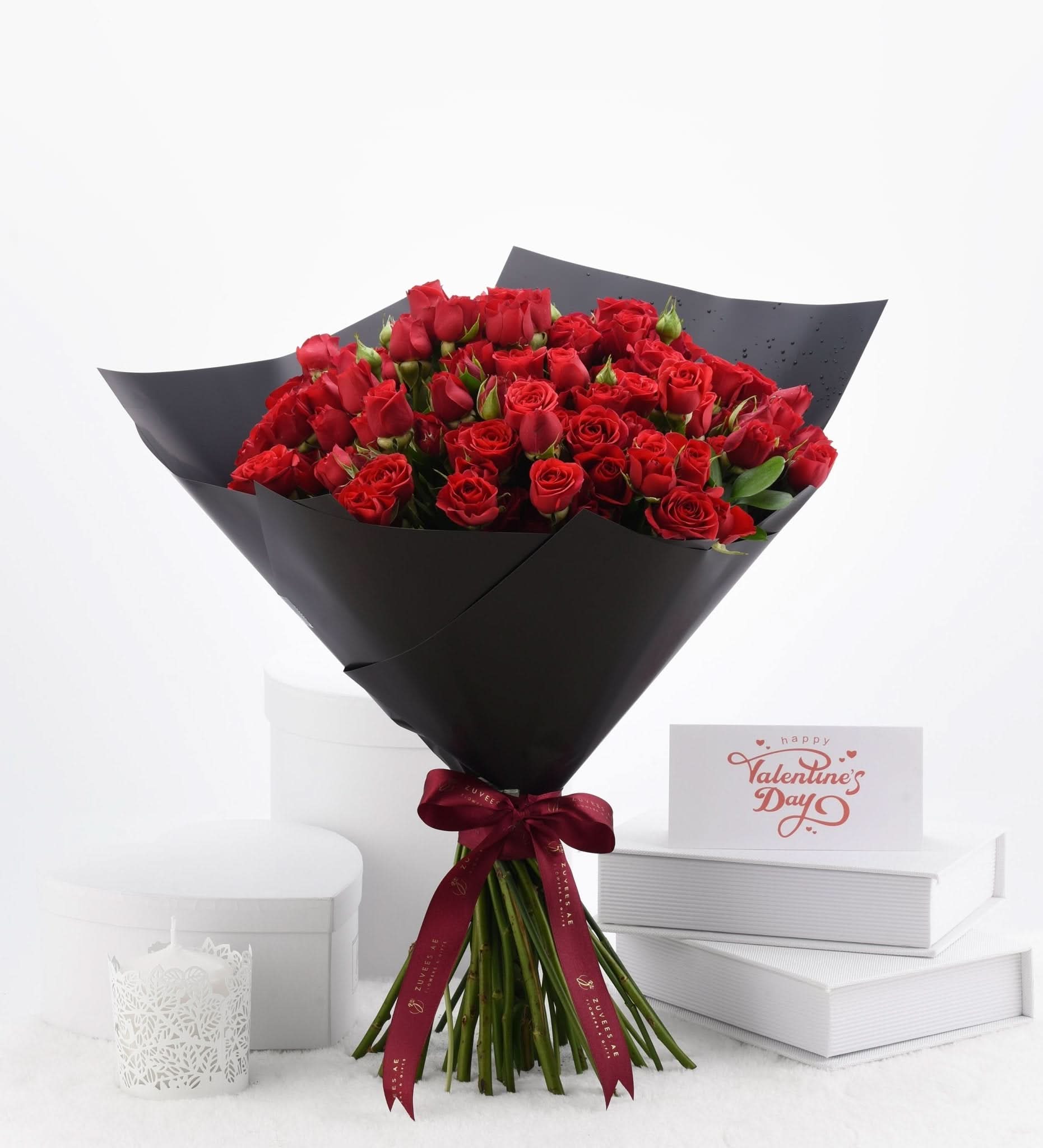 Luxurious red roses in sleek black wrap, Valentine’s Day card nearby.