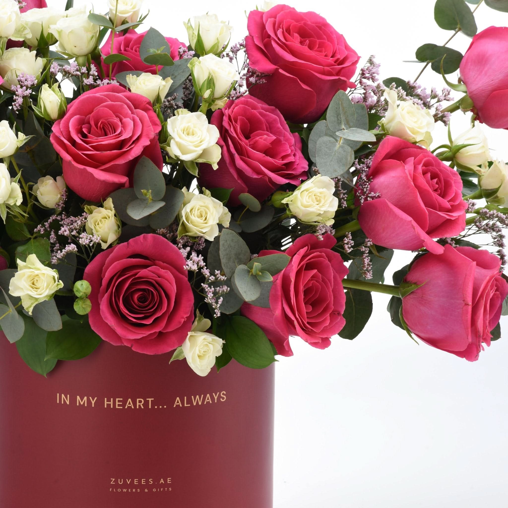 Vibrant pink and white roses with eucalyptus in a maroon vase reading "In My Heart... Always".