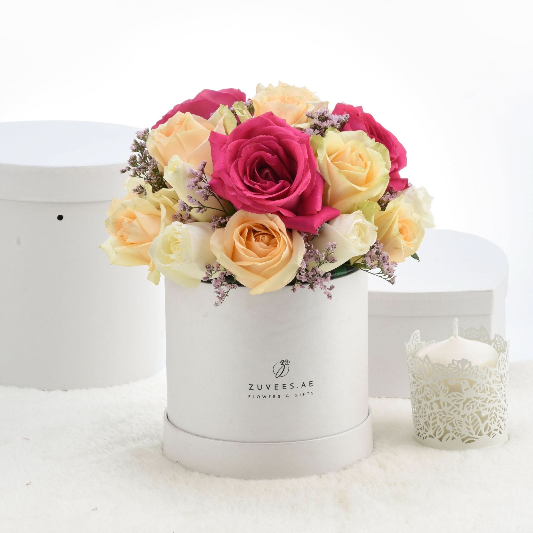 Vibrant pink and yellow roses in white box, accented with lavender sprigs.
